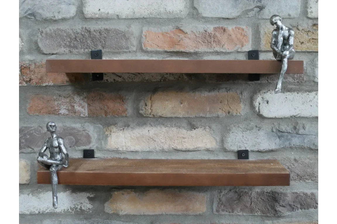 Wall mounted wooden shelves with metal brackets and metallic figurines, brick background