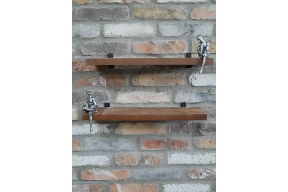 Wall mounted wooden shelves with silver figurines against brick background