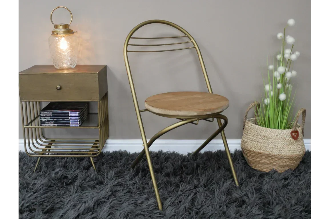 Gold metal and wood chair with round seat next to brass metal side table and woven basket planter