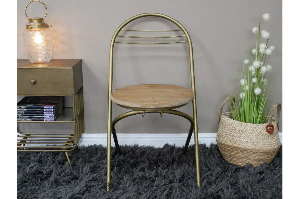 Gold metal chair with round wooden seat on shaggy rug beside lamp table and woven basket plant