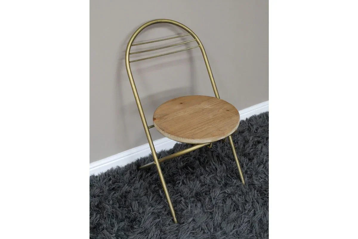 Gold metal folding chair with round wooden seat on grey shaggy rug