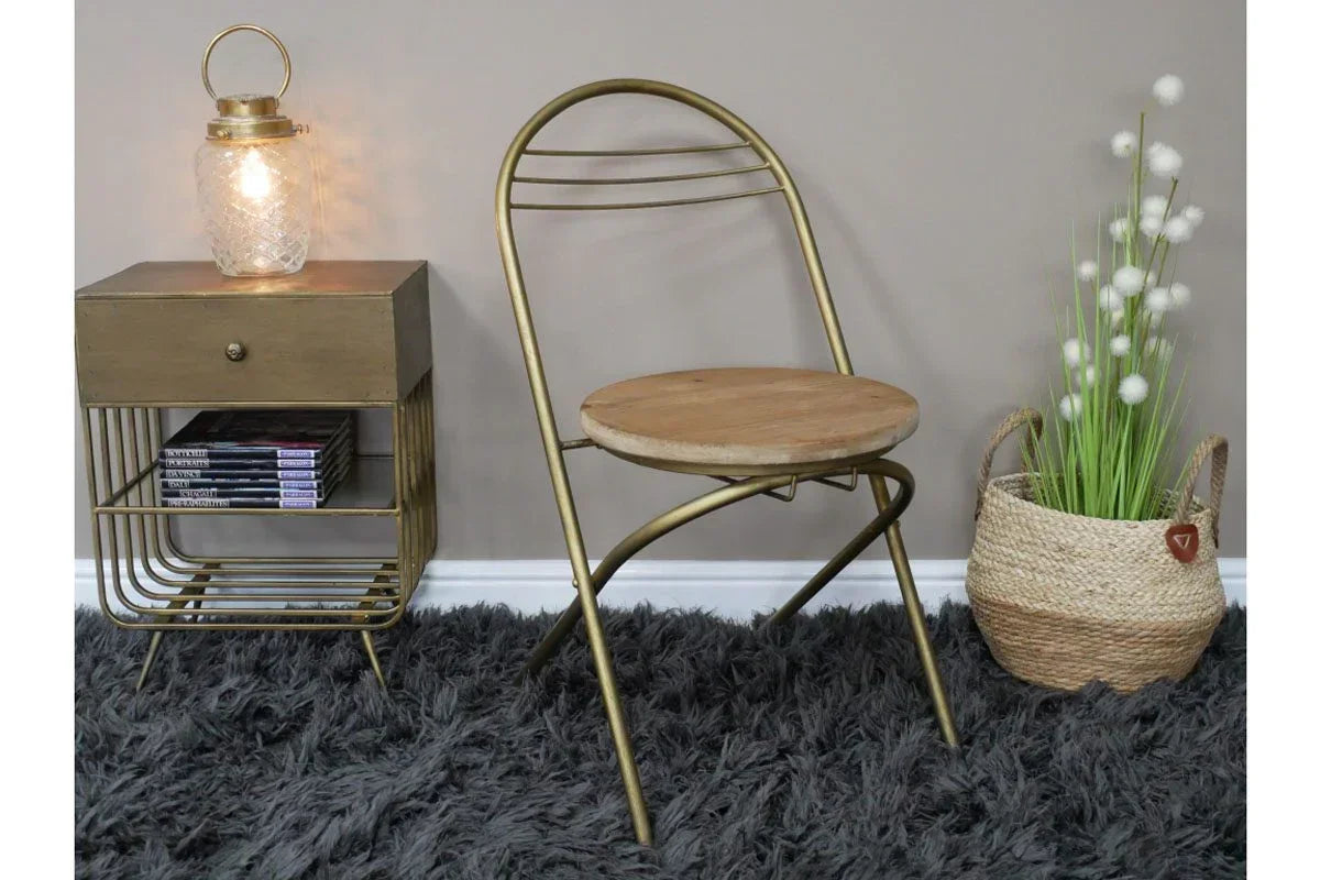 Metal and wood folding chair beside gold side table and woven basket with faux plant