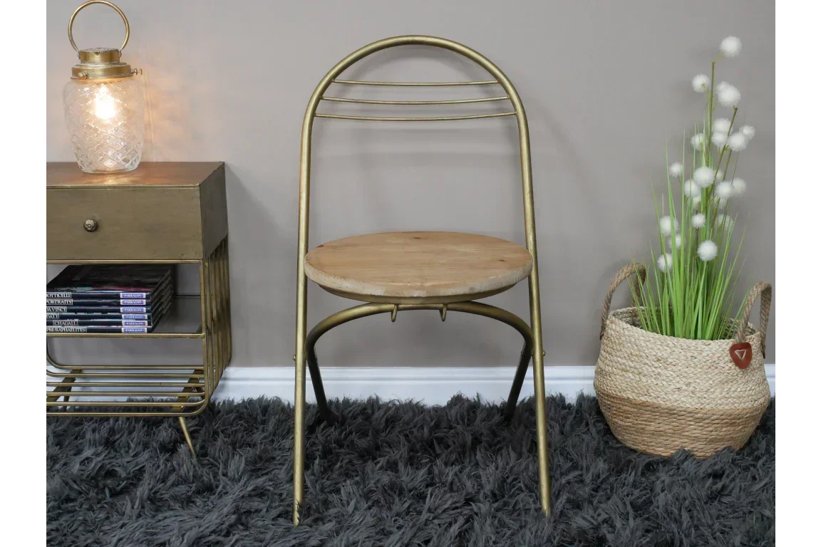 Gold metal dining chair with round wooden seat on grey rug