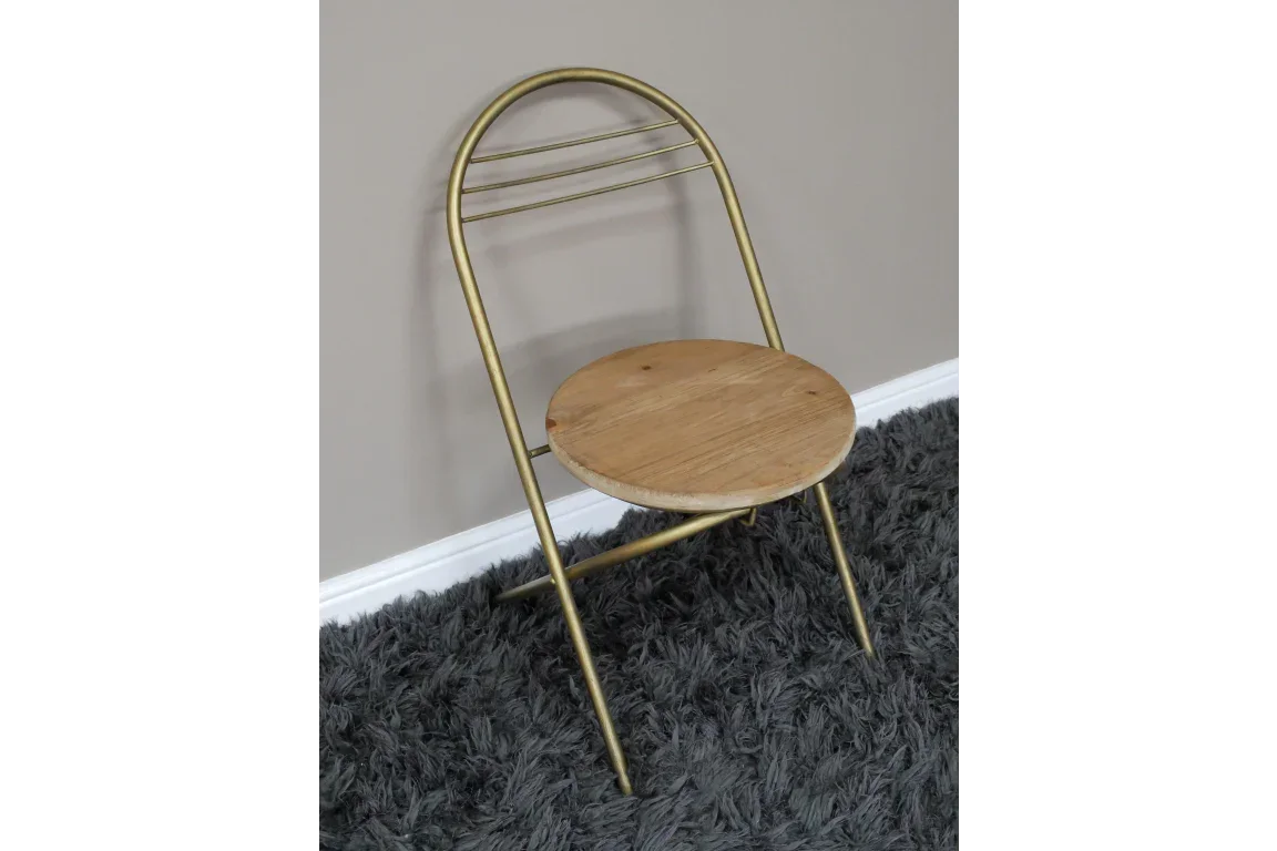 Gold metal folding chair with round wooden seat on grey shaggy rug