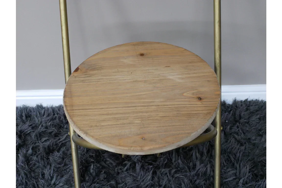 Round wooden side table with gold metal legs on grey shaggy rug