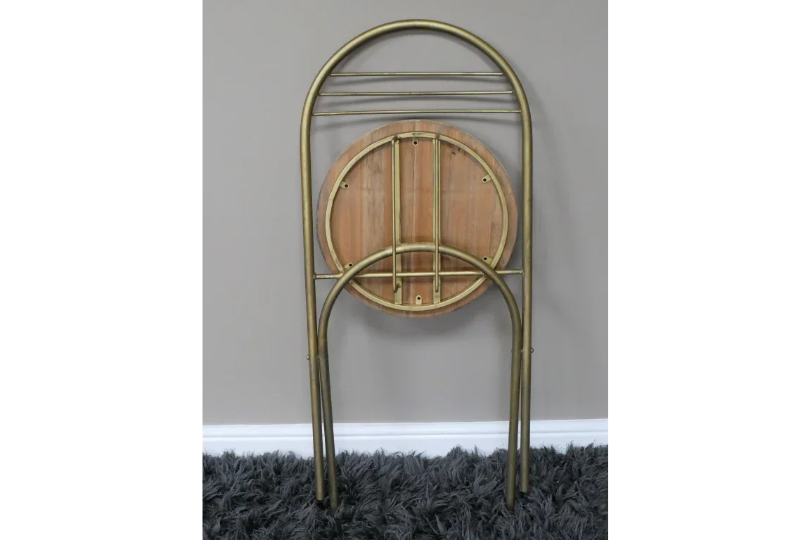 Folding round side table with wood top and gold metal frame stored upright on carpet