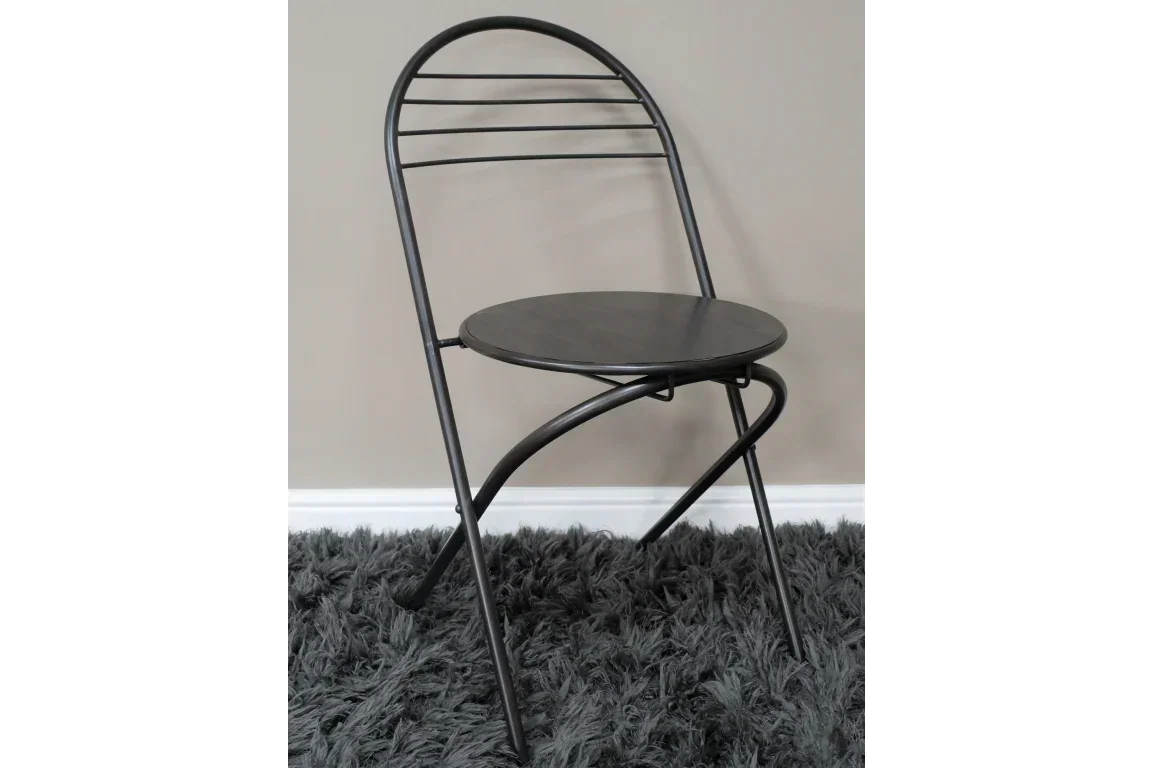 Black metal folding chair with round seat on grey textured rug