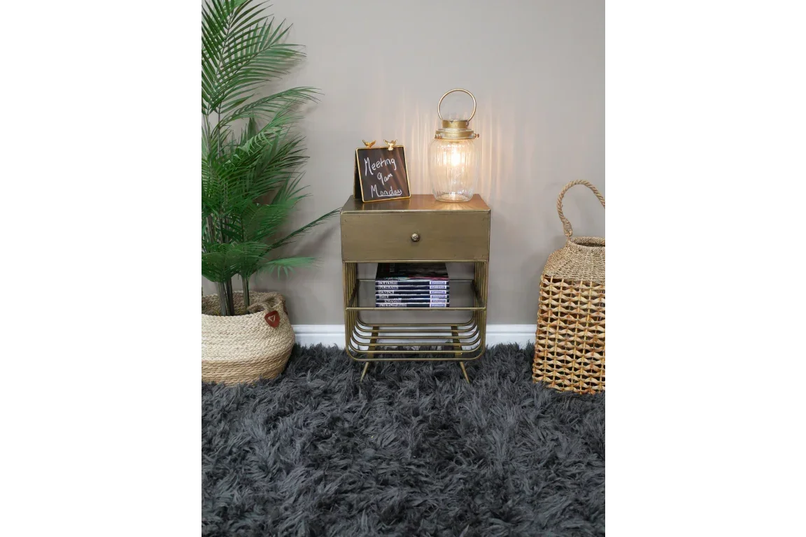 Brass bedside table with drawer, books, and lantern styled on grey shaggy rug