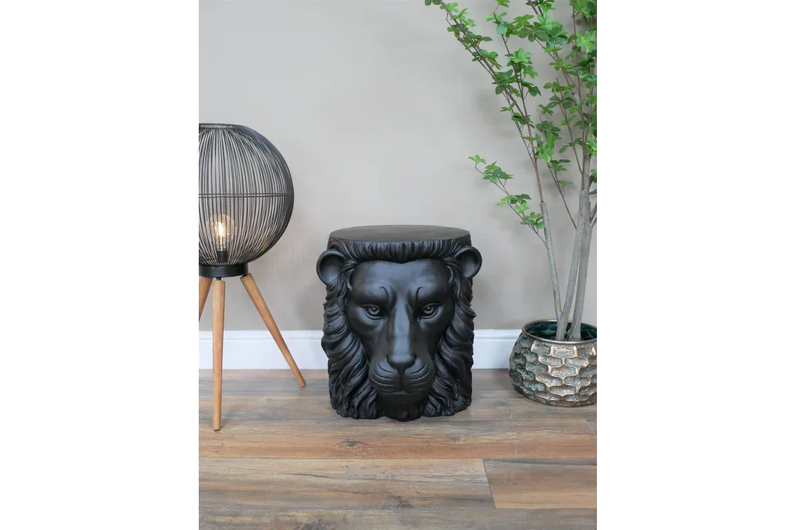 Black lion head stool beside modern lamp and plant on wood floor