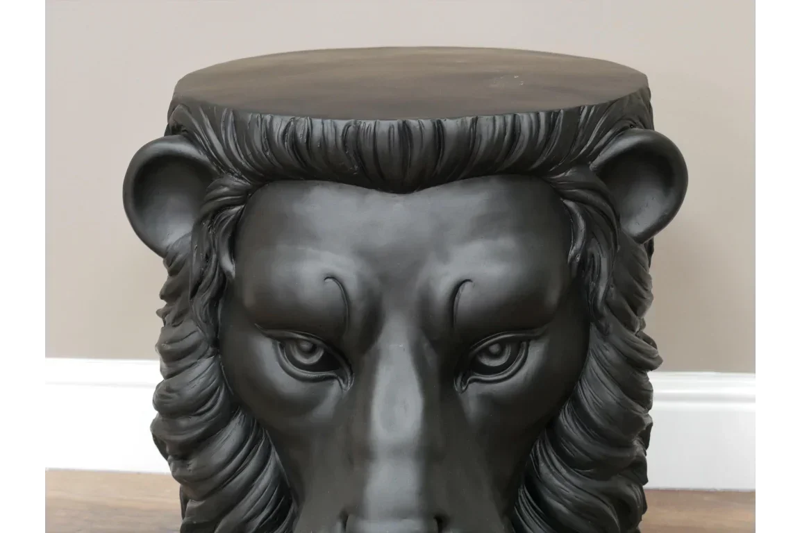 Black lion head side table with sculpted features on wooden floor near neutral wall
