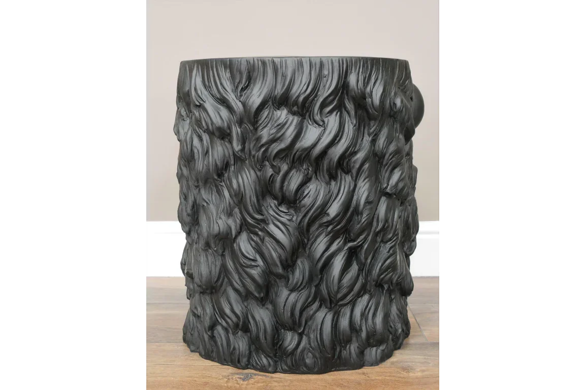 Black side table with textured faux fur pattern, cylindrical design on wooden floor