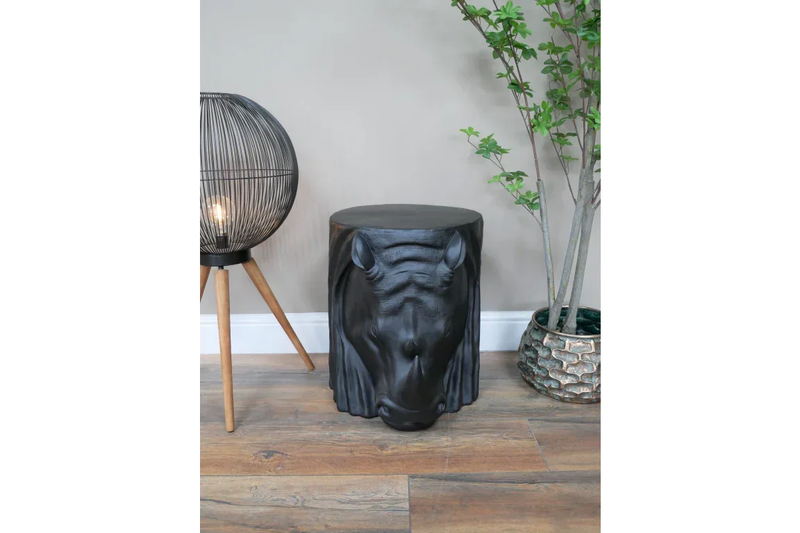 Black horse head side table on wood floor beside modern lamp and plant pot