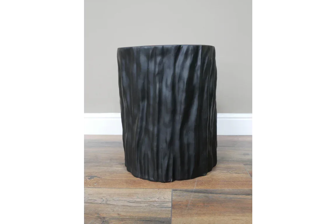 Black textured side table with a wavy surface, placed on a wooden floor