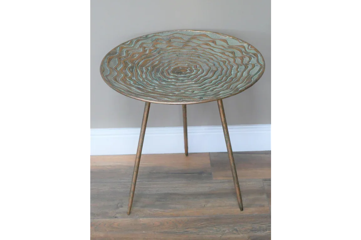 Round metal side table with embossed swirl pattern and three tapered legs