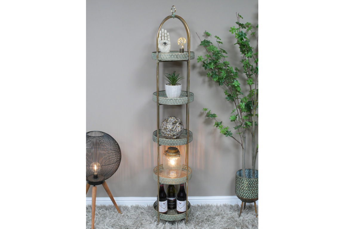Tall Moroccan style 5 tier metal shelves with decorative items, standing on gray shag carpet, beside floor lamp and potted