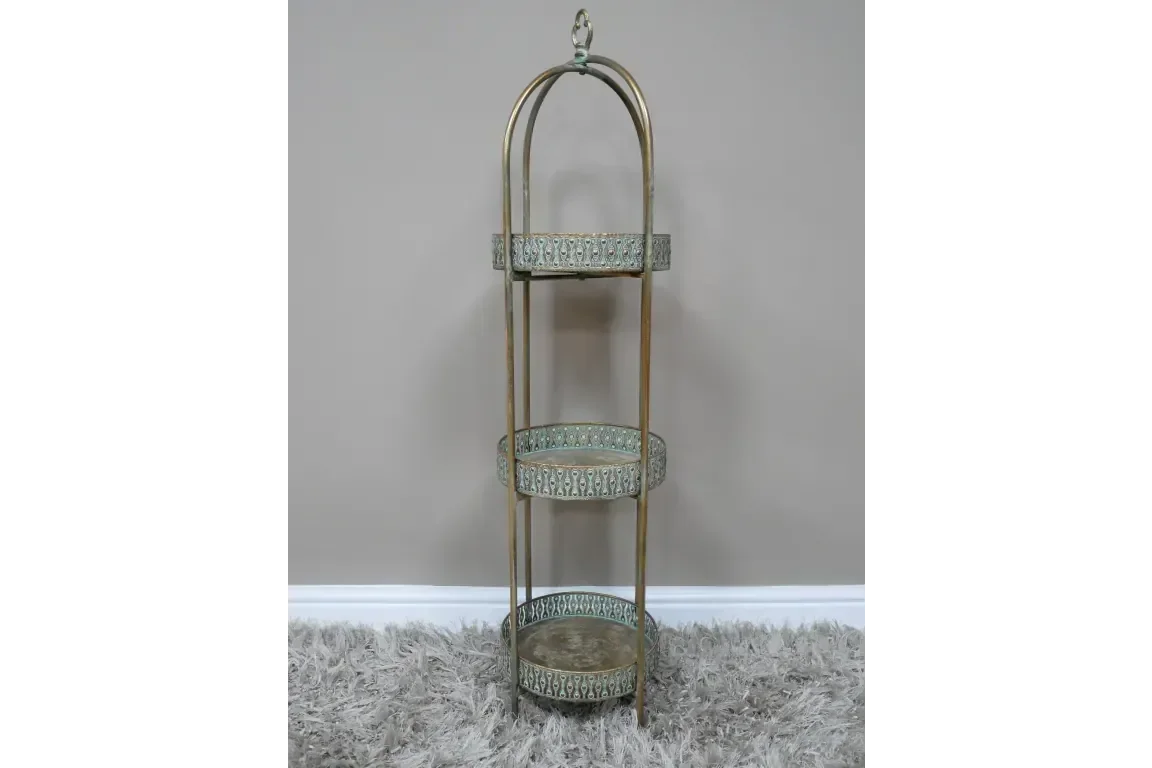 Three tier metal shelving unit with ornate trim and arched frame on carpet