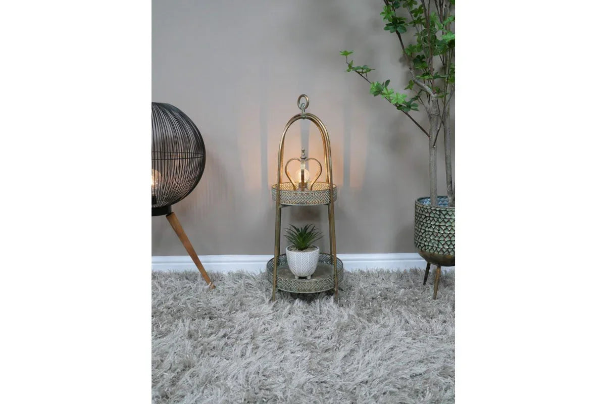 Two tier gold metal side table with lamp and plant on shaggy rug beside indoor plants