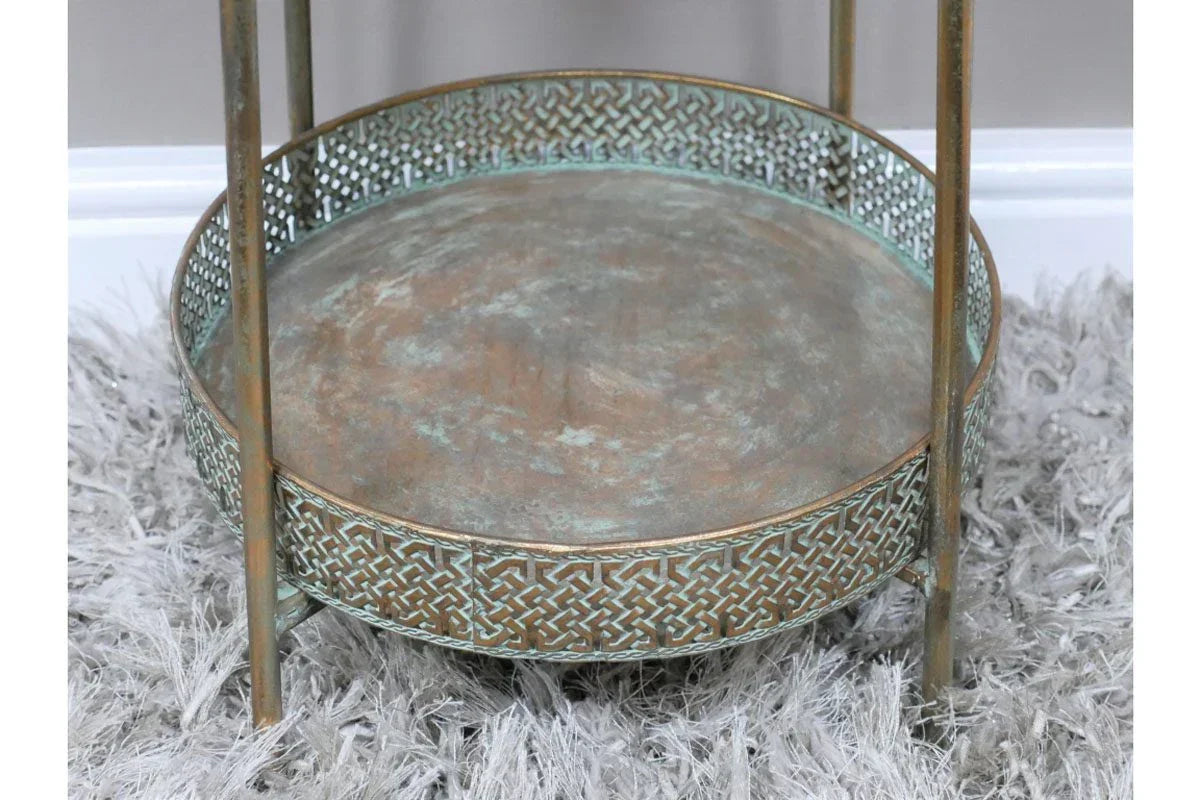 Distressed metal side table with decorative patterned rim on textured grey rug