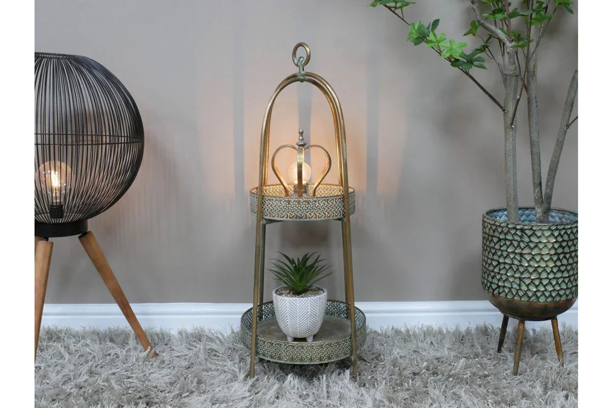 Brass floor lamp with two shelves, decorative bulb, and potted plant on grey rug