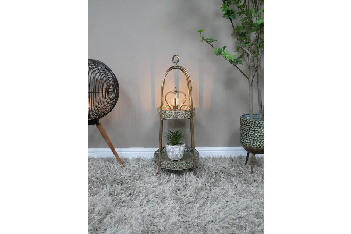 Gold two tier side table with decorative lamp and potted plant on soft grey rug