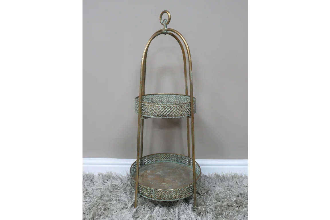 Two tier gold metal display stand with decorative trays on grey carpet