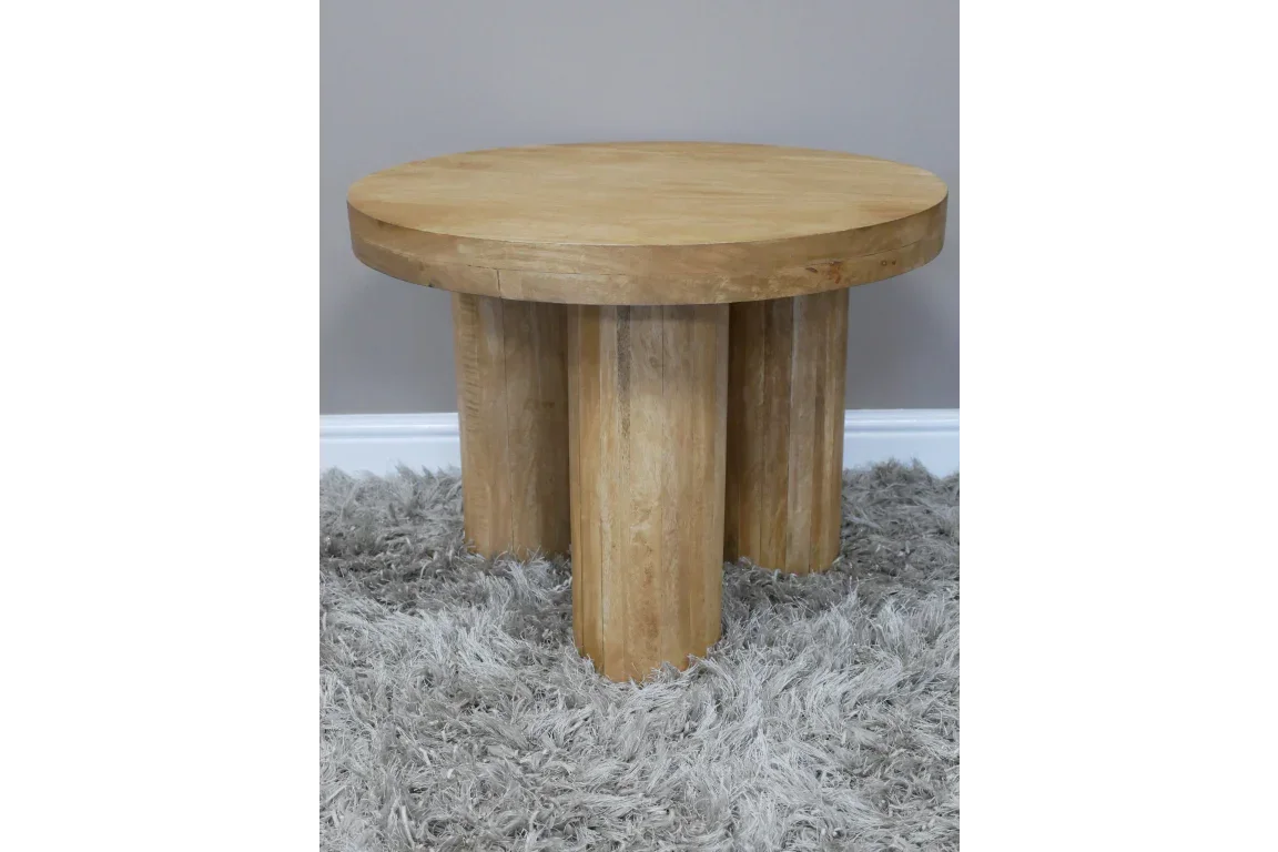 Round wooden coffee table with thick cylindrical legs on grey shaggy rug