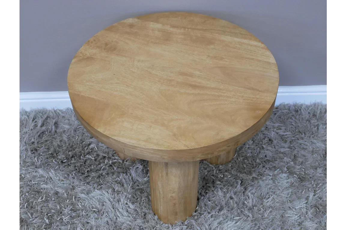 Round wooden coffee table with three legs on gray shaggy rug
