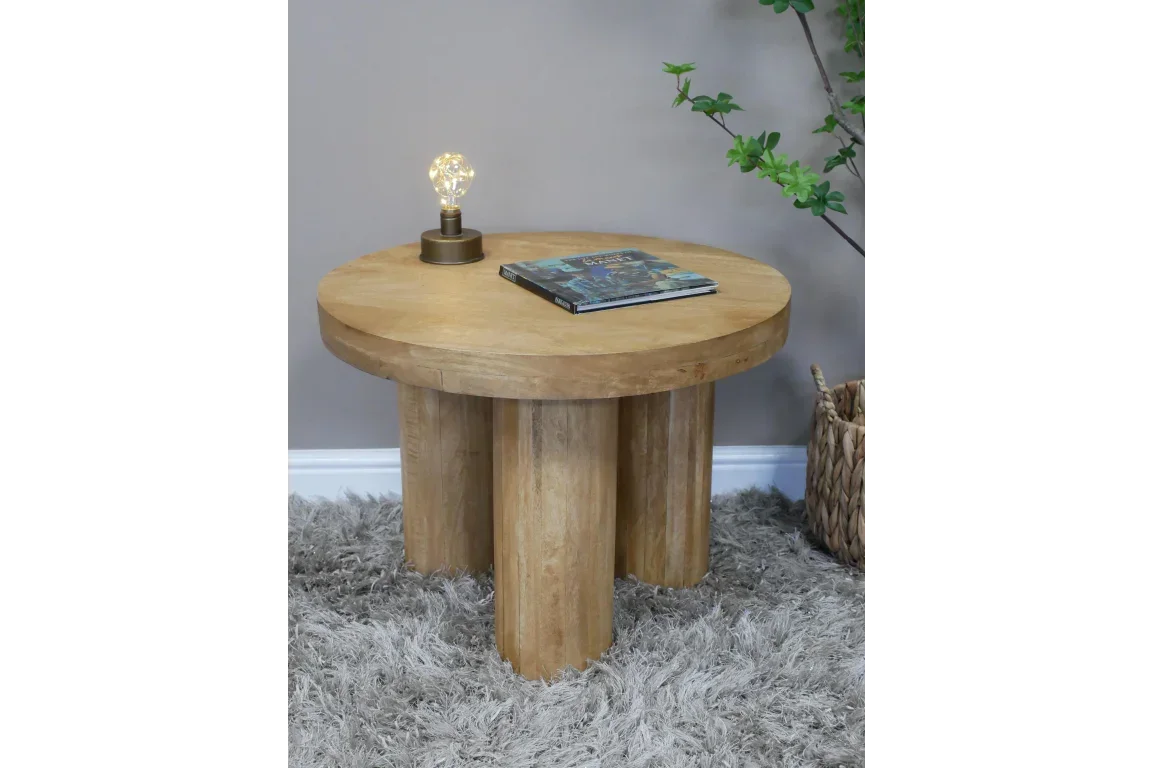 Round oak coffee table with four cylinder legs, lamp and book on shaggy rug floor