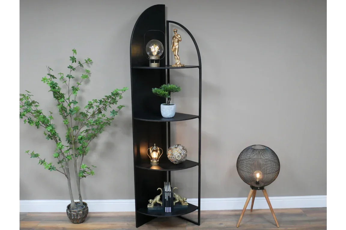 Black metal corner shelving unit styled with decor, beside plant and floor lamp