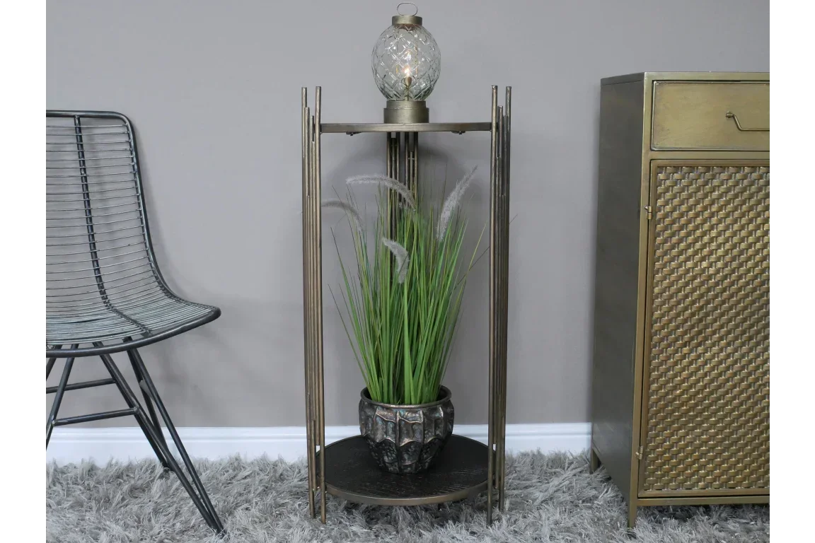 Bronze accent table with glass lamp and potted artificial grass on grey rug