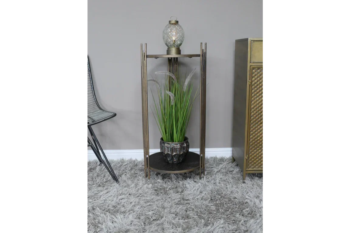 Gold metal side table with glass lamp and potted plant on grey shag rug