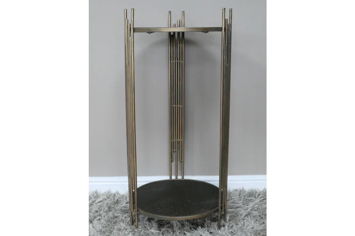 Metal side table with round dark wood top and tall vertical gold frame on a grey rug
