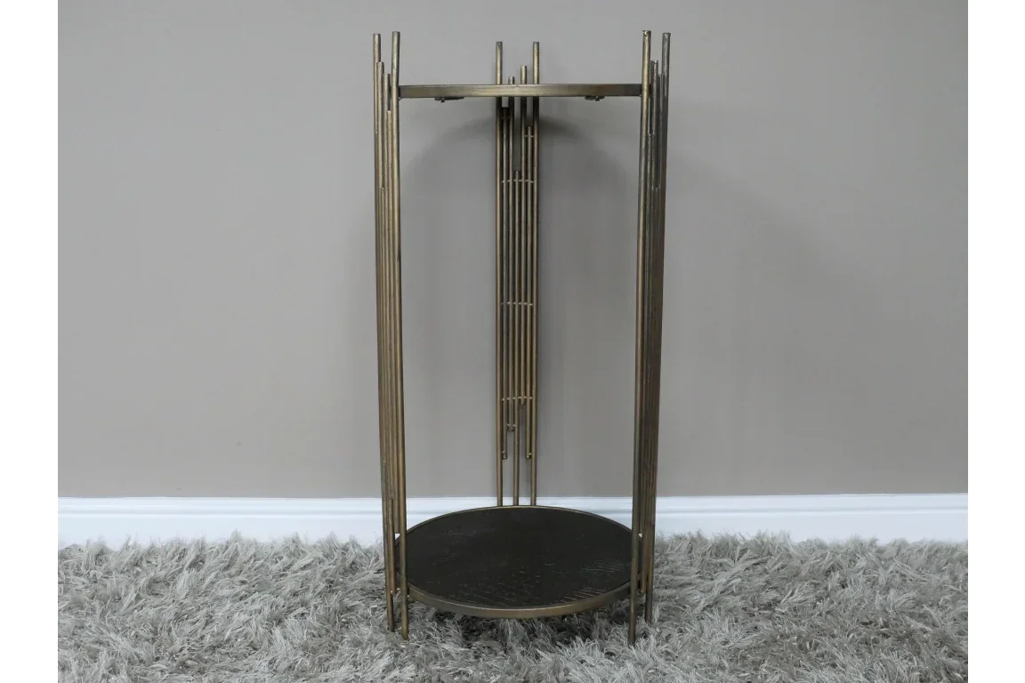 Gold metal side table with round black top and vertical rod legs on grey carpet