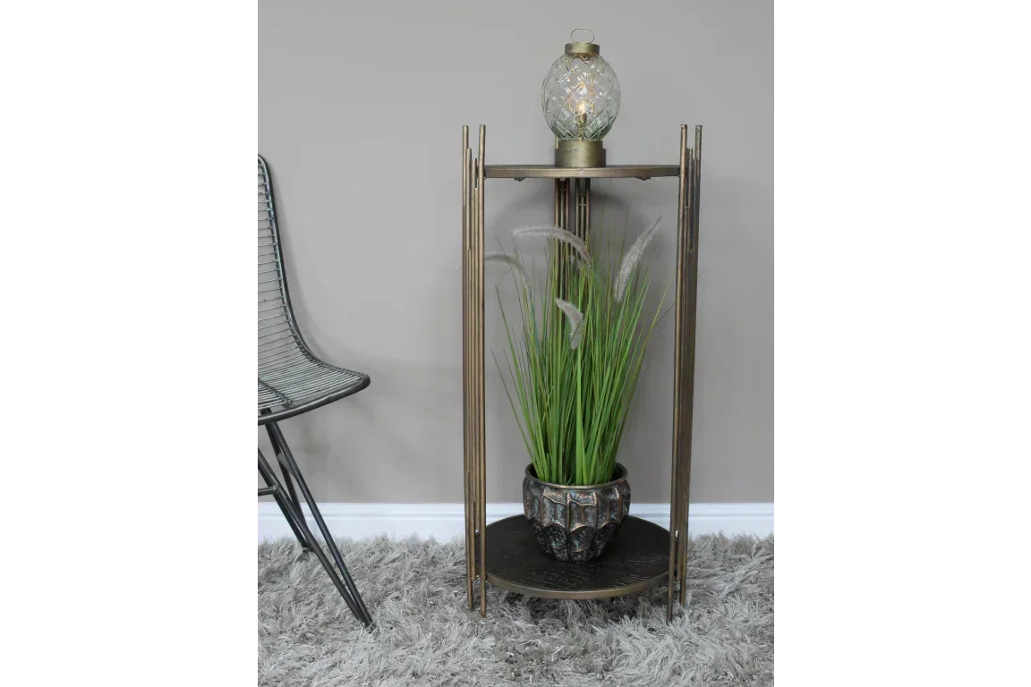 Bronze metal side table with glass lamp and potted artificial grass plant in living room
