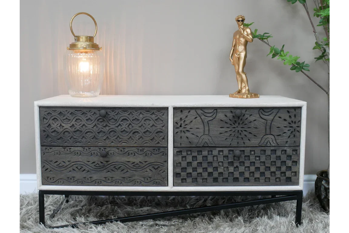 Carved wood sideboard with black patterned drawers, gold lamp and sculpture on top