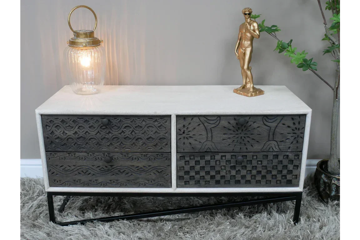 Carved wood sideboard with white frame, patterned drawers, glass lamp and gold statue decor