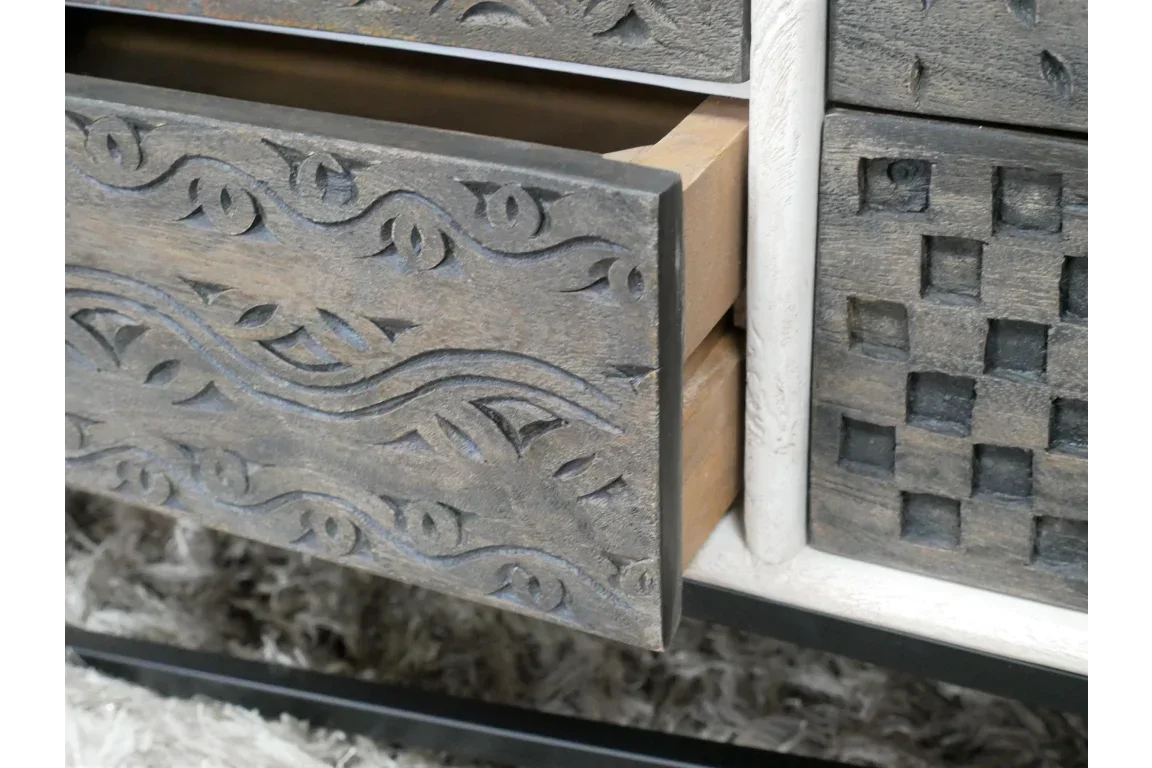 Carved wood drawer front with intricate floral pattern on a textured storage cabinet