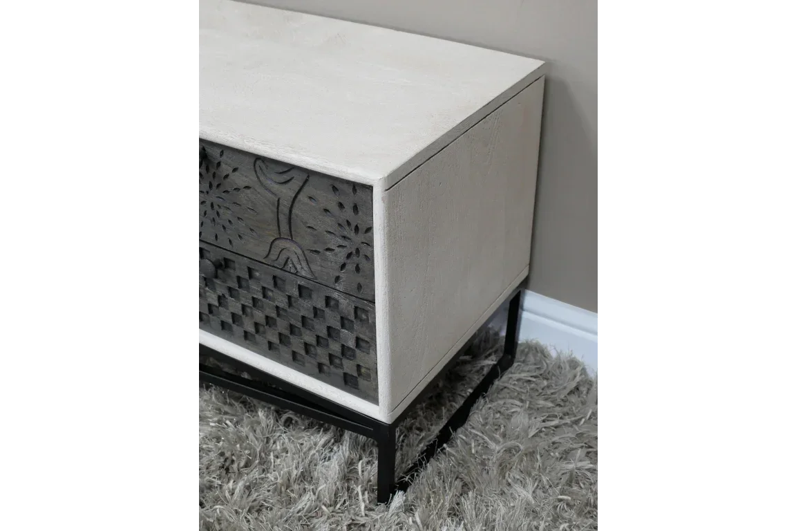 Wooden bedside table with carved drawers and black metal legs on gray rug