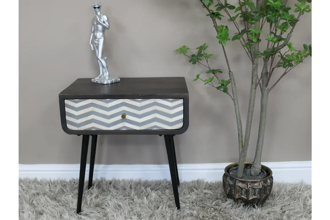 Chevron patterned bedside table with black legs beside potted plant on grey rug