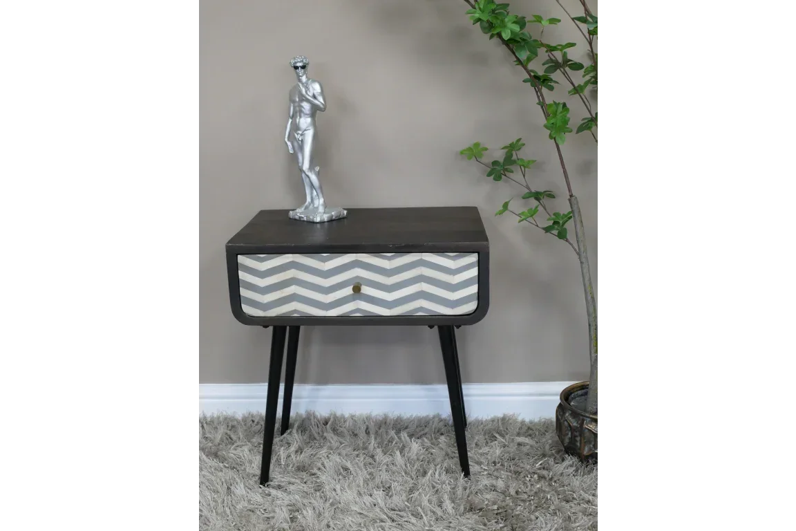 Chevron pattern bedside table with black legs and decorative statue in modern living space