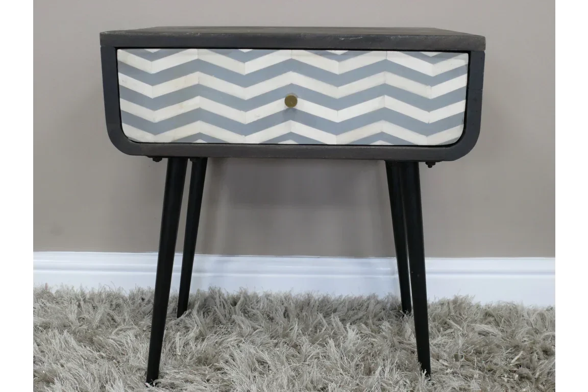 Modern bedside table with chevron patterned drawer and black angled legs on a grey rug