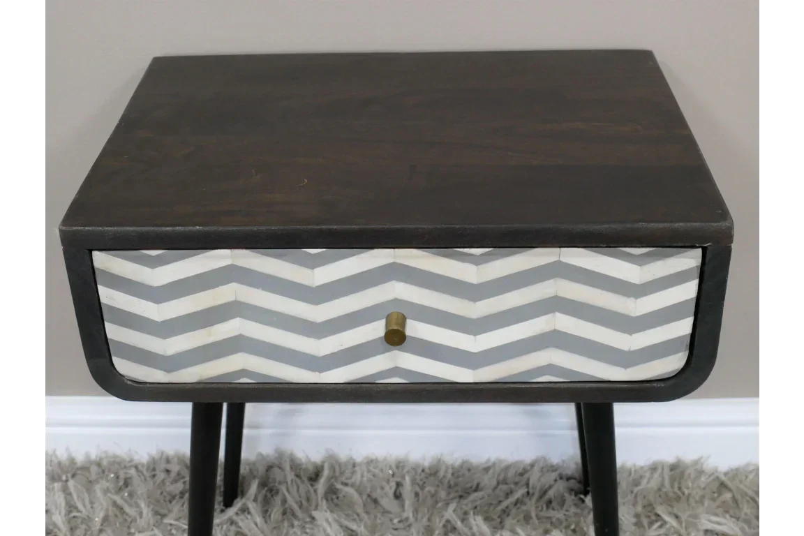 Modern wooden bedside table with chevron pattern drawer and brass knob on shaggy rug