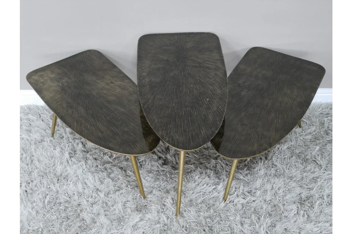 Set of three brass side tables with textured tops and gold legs on grey rug