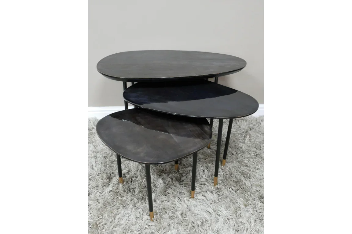 Set of three nesting coffee tables with black metal legs and gold tips on grey rug