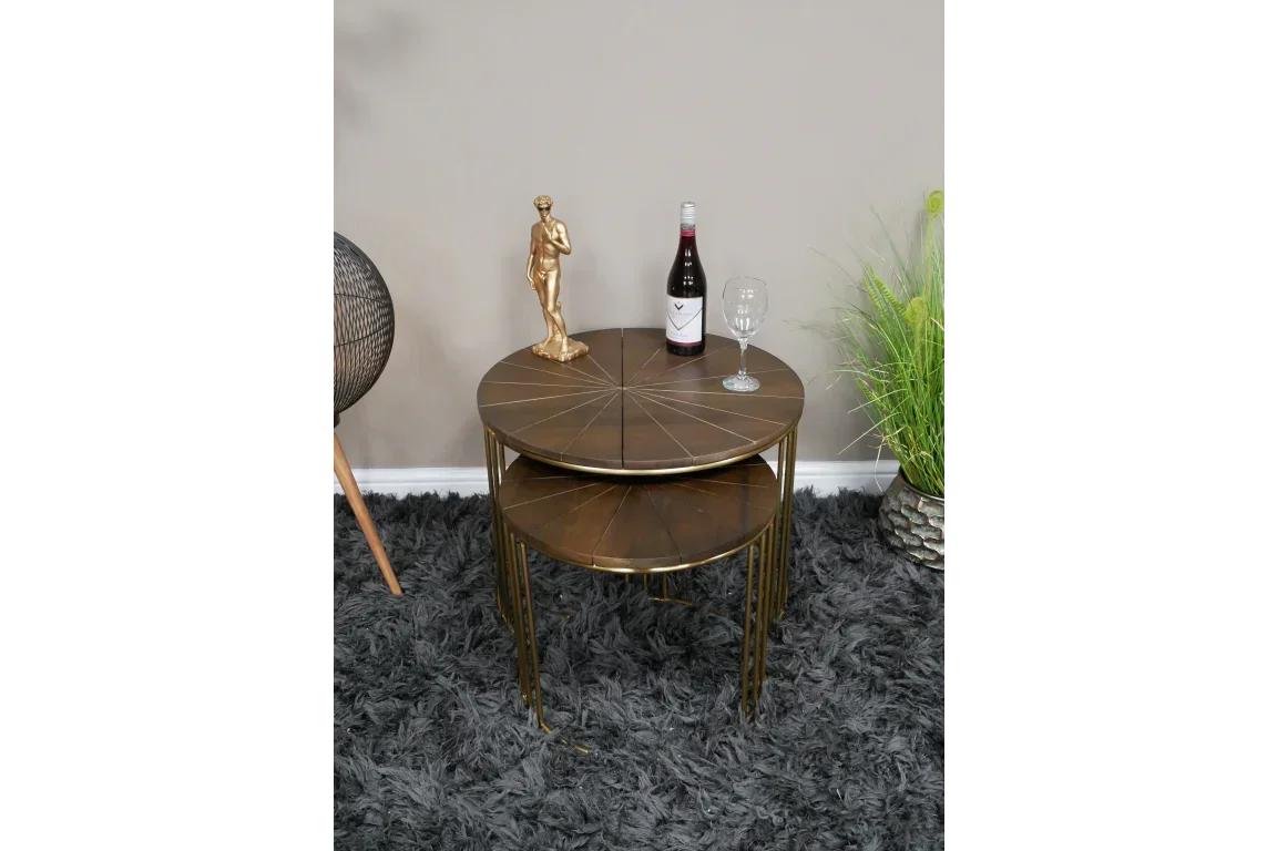 Round bronze nesting tables with metal legs, styled with decor on a grey rug