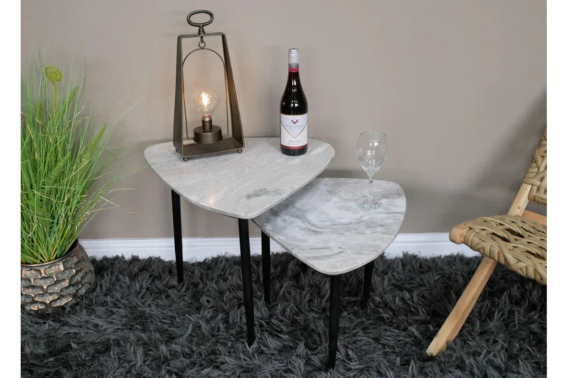 Set of two marble nesting tables with black legs styled with lamp, wine bottle and glass