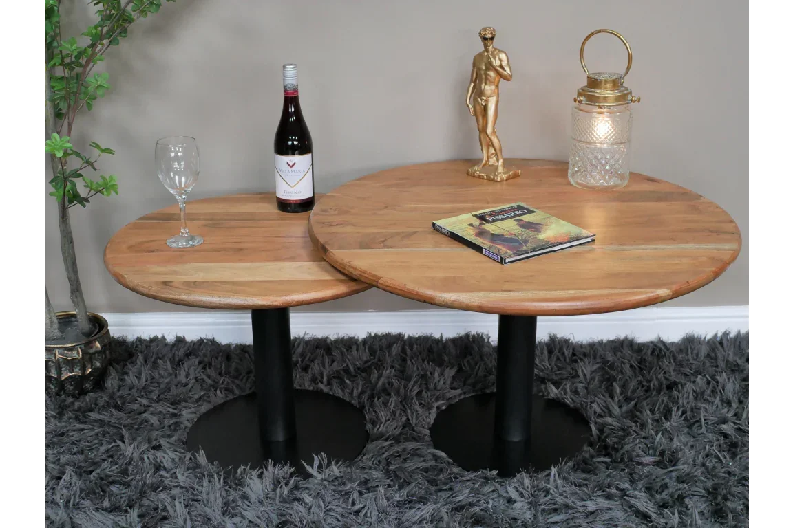 Round wood nesting coffee tables with black metal bases on grey rug, decorated with ornaments
