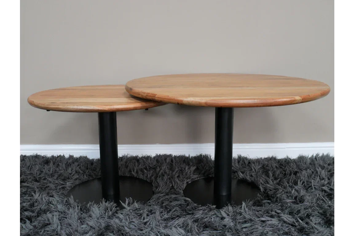 Set of two round wooden coffee tables with black metal pedestal bases on grey rug