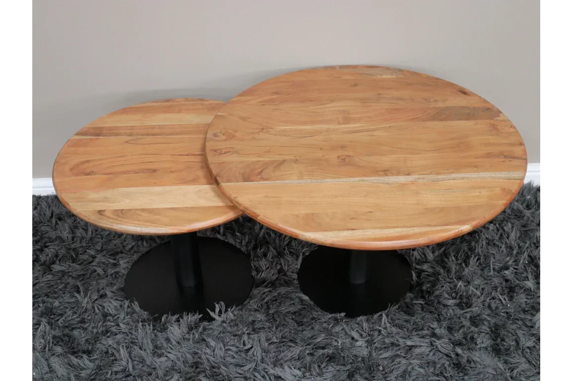 Pair of round wooden coffee tables with black pedestal bases on grey shaggy rug