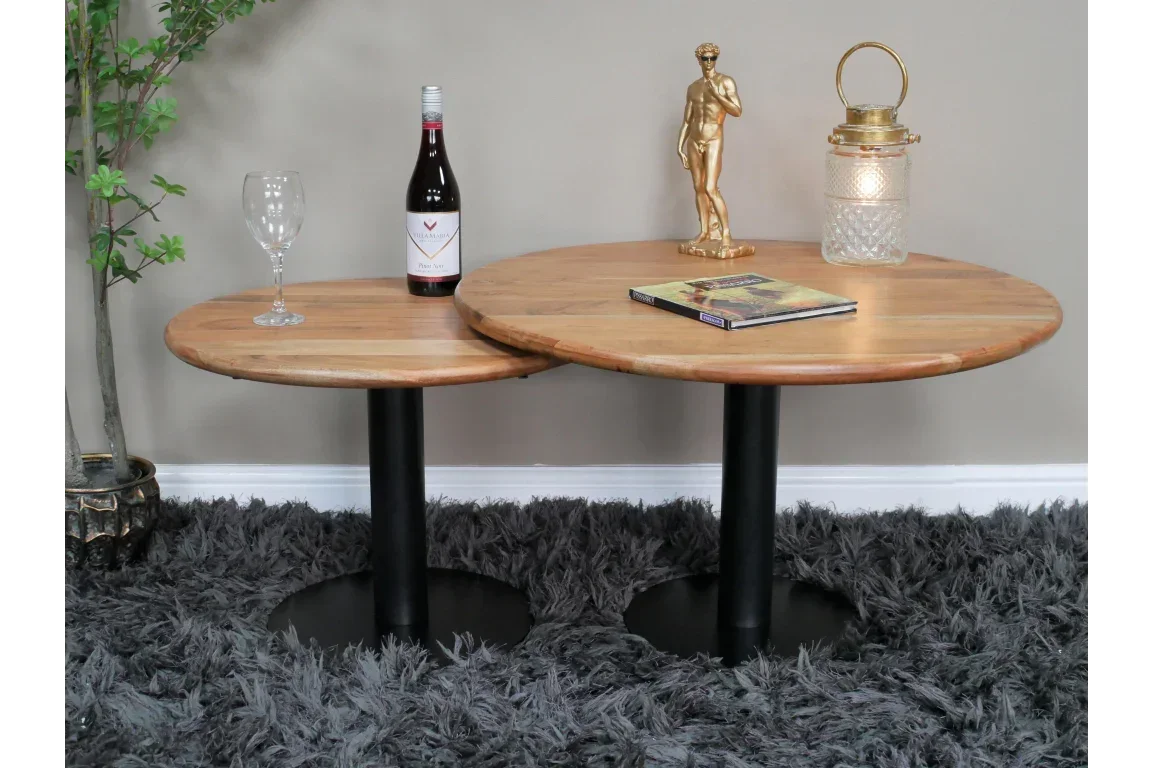 Round wooden coffee tables with black metal bases styled with wine, book and decor